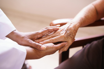 Infimière tenant les mains d'une personne âgée