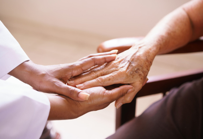 Infimière tenant les mains d'une personne âgée