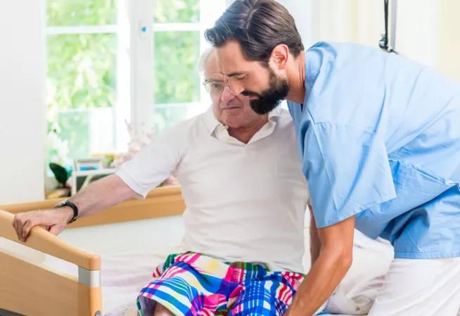 Infirmier aidant une personne à sortir de son lit